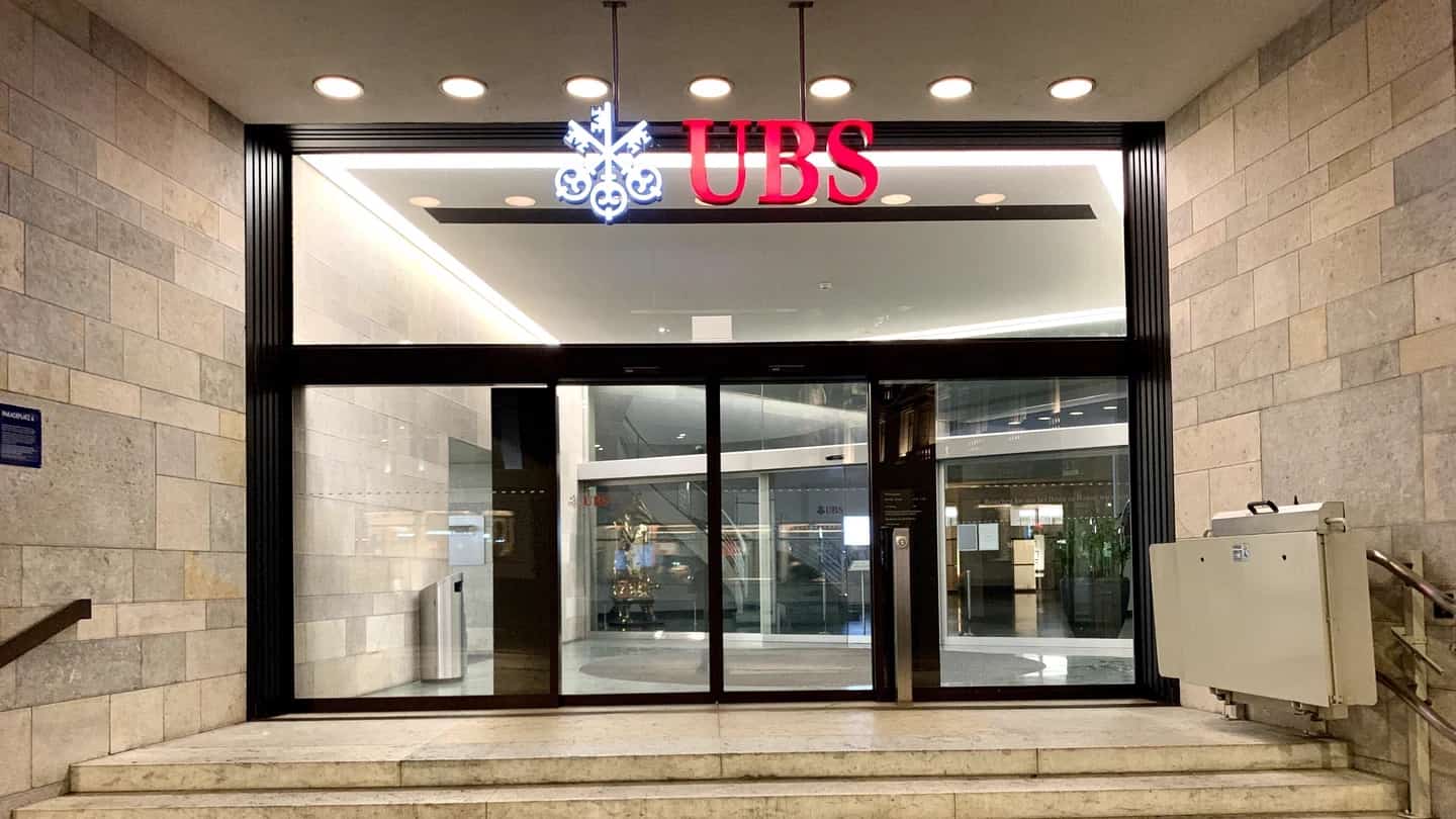 Entrada da sede do UBS na Paradeplatz, em Zurique, com o logotipo do banco sobre as portas de vidro.