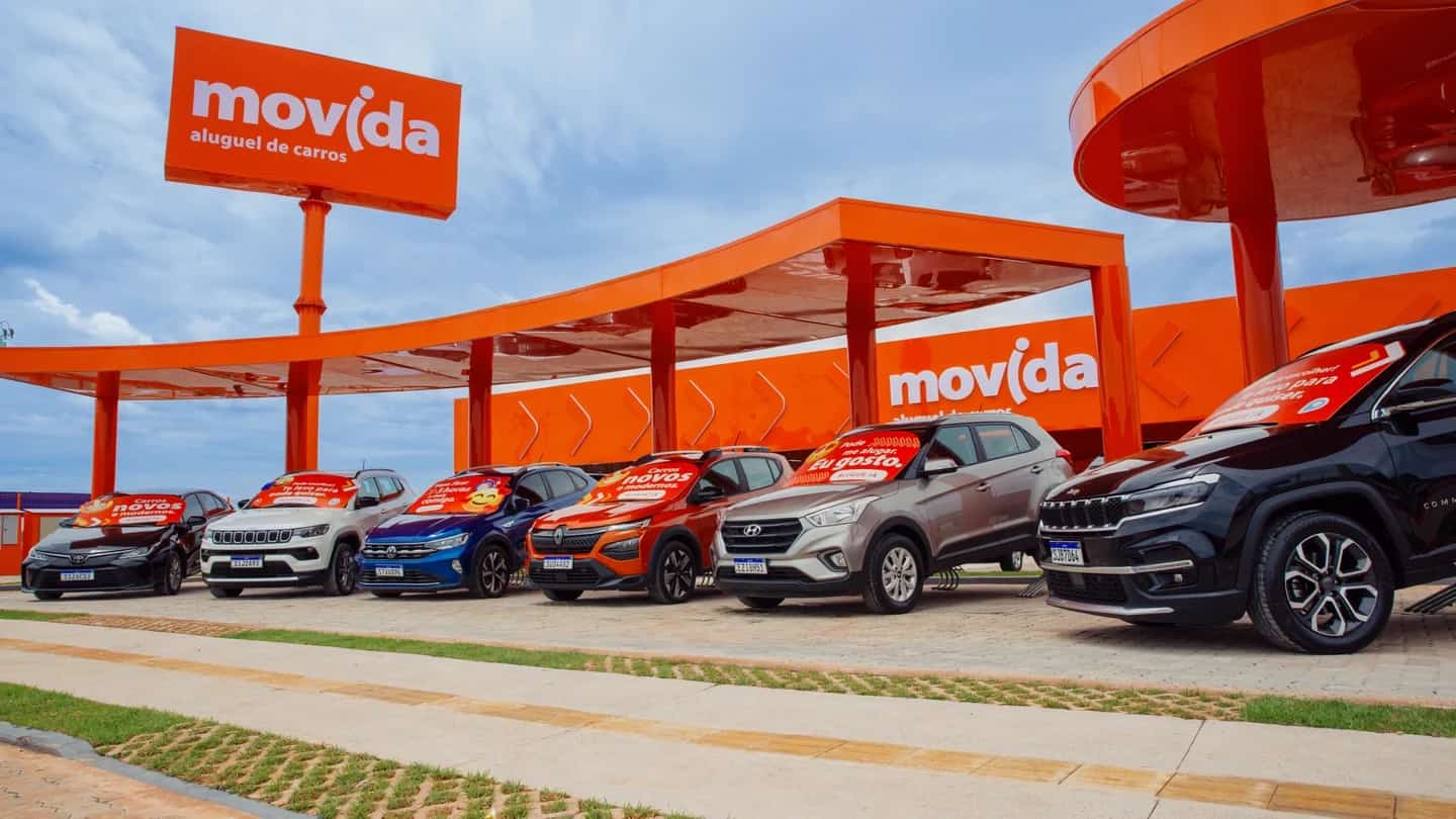 Loja da Movida com carros alinhados em pátio e letreiro da marca sobre a cobertura laranja.