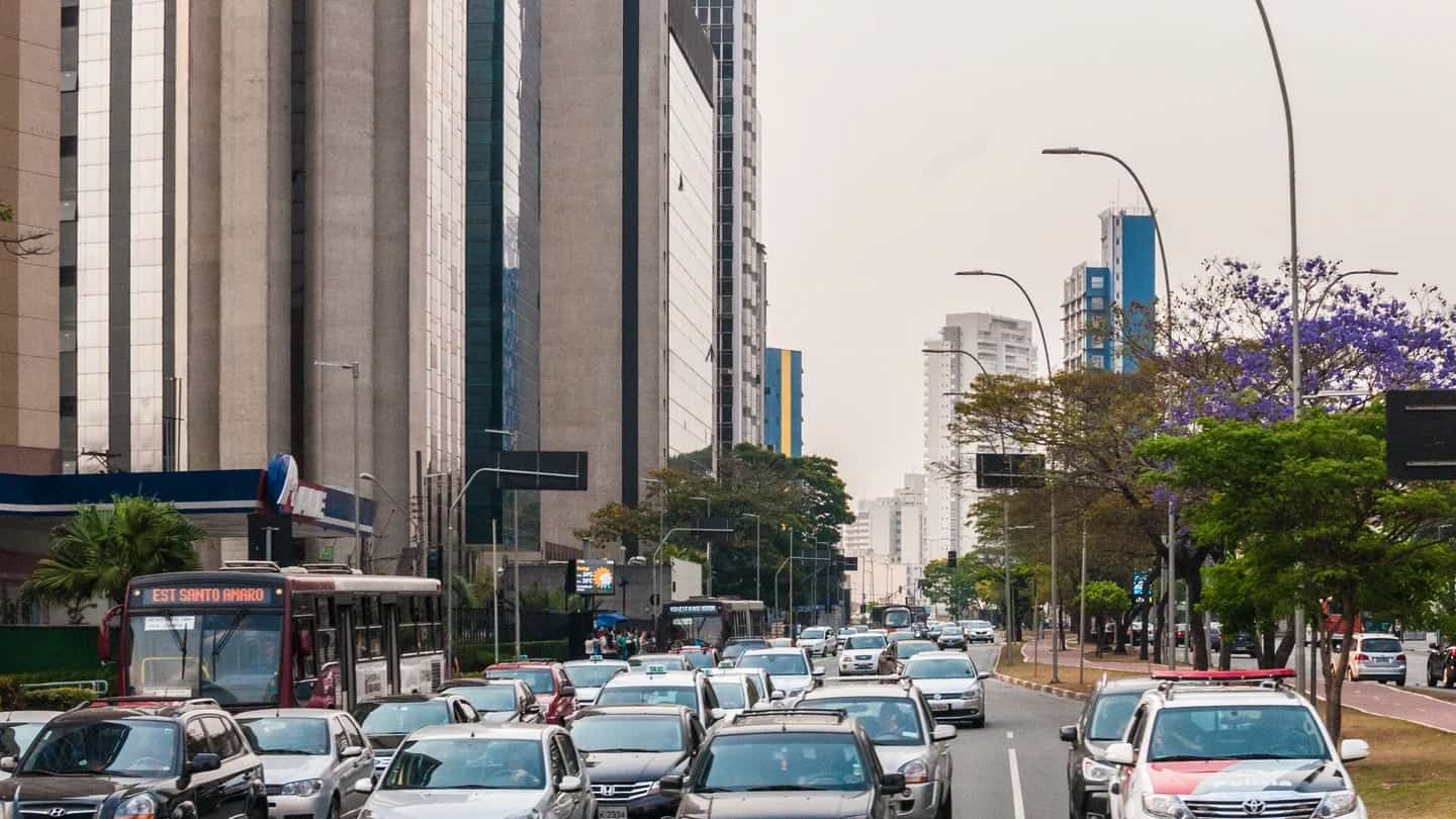 Avenida Faria Lima, em São Paulo, com prédios comerciais e trânsito intenso sob céu encoberto.
