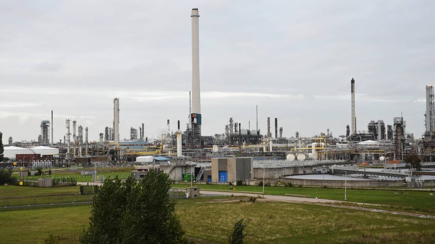 Vista da refinaria da Shell em Pernis, nos Países Baixos, com torres de destilação e chaminé ao fundo