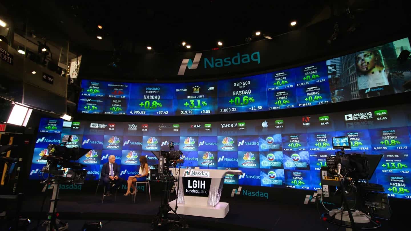 Estúdio de TV da Nasdaq com telões de cotações e dados de mercado ao fundo