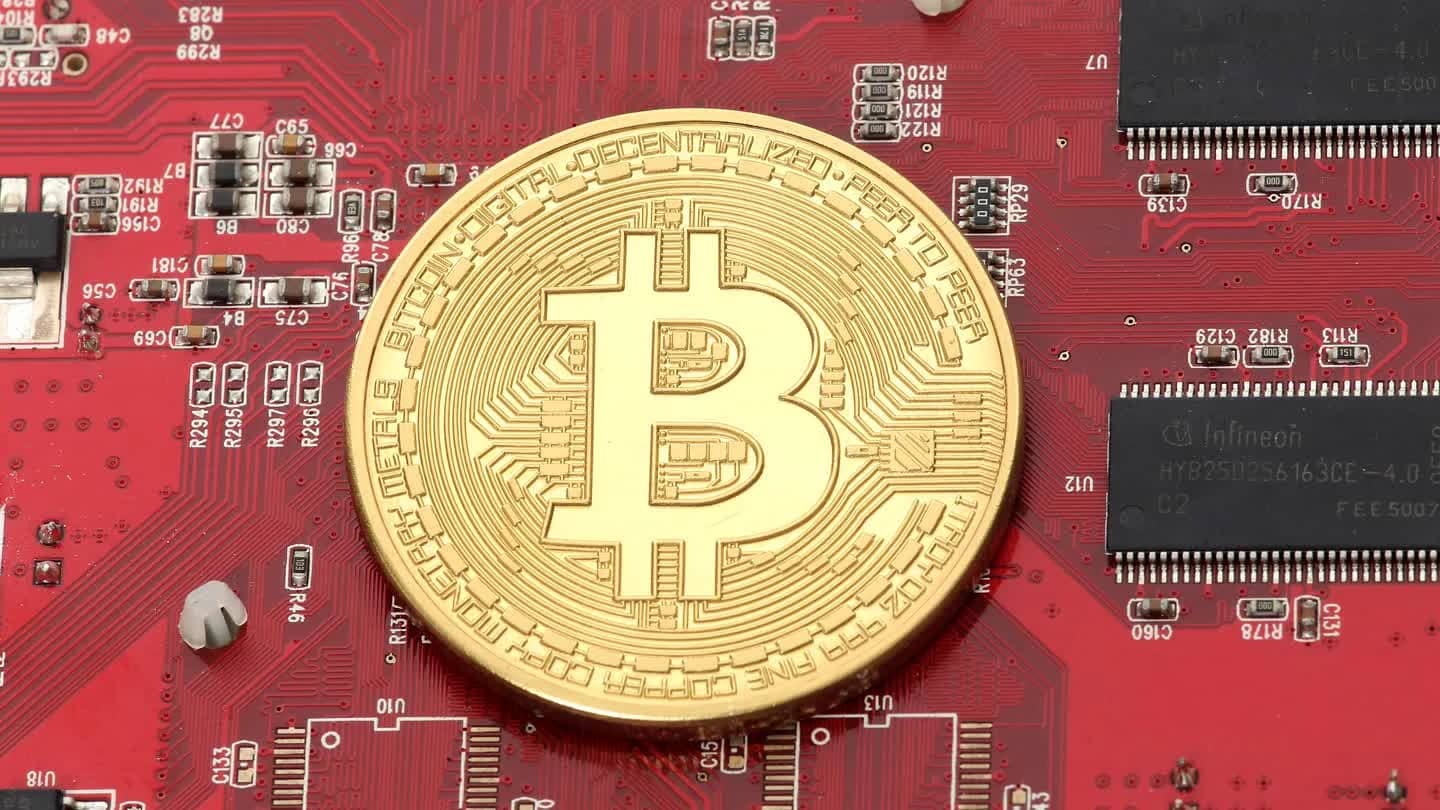 Moeda física de bitcoin banhada a ouro sobre placa de circuito impresso vermelha