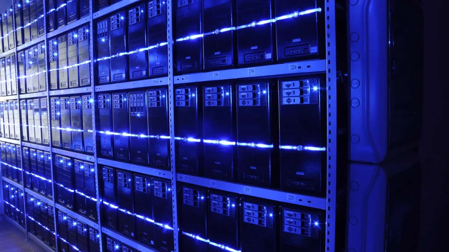 Corredor de servidores iluminado de azul, em sala-cofre de data center