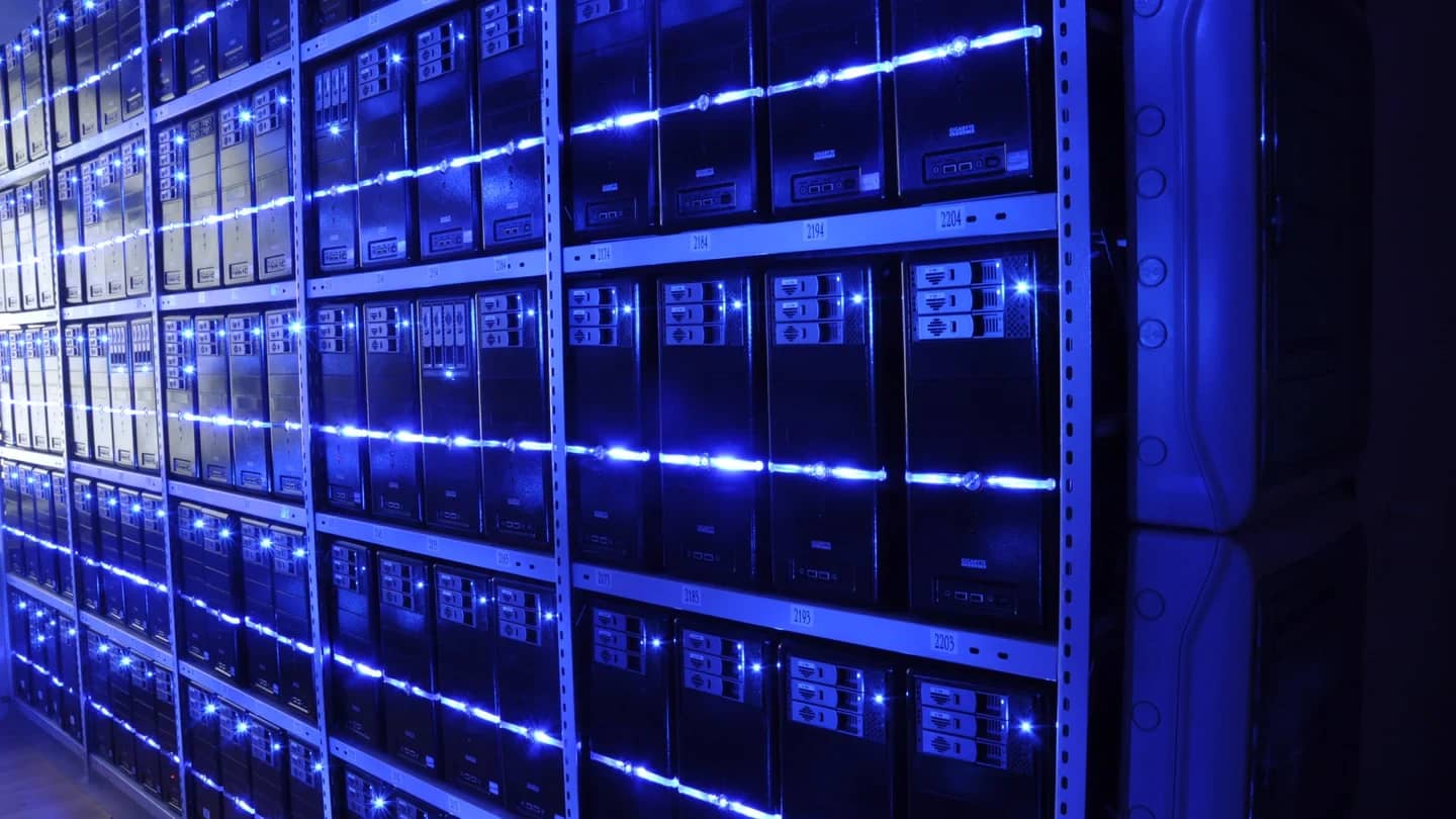 Corredor de servidores iluminado de azul, em sala-cofre de data center