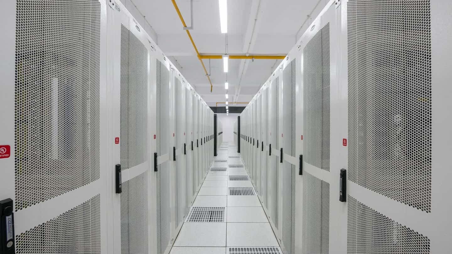 Corredor de gabinetes de servidores em data center, com portas perfuradas e piso elevado