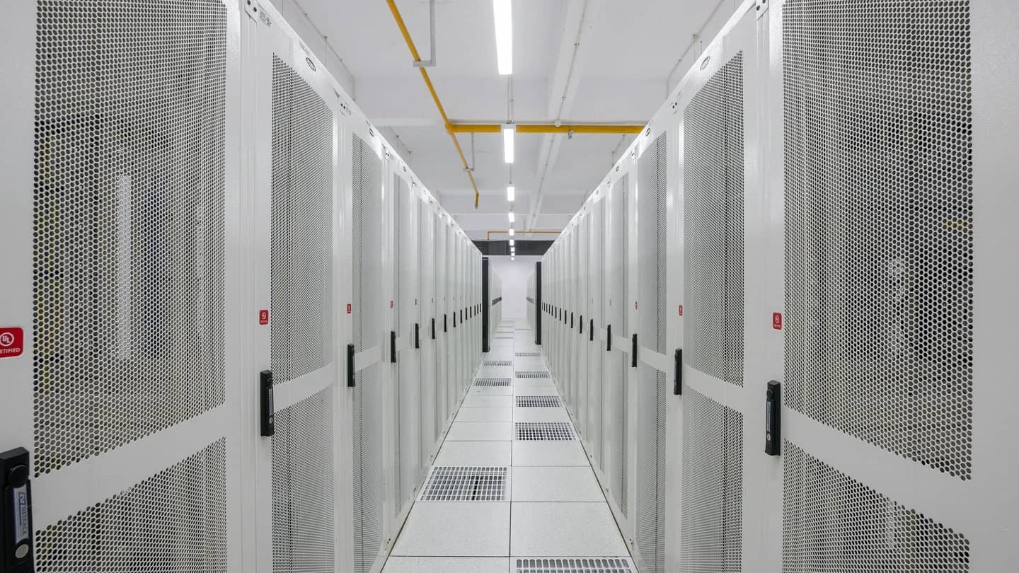 Corredor de gabinetes de servidores em data center, com portas perfuradas e piso elevado