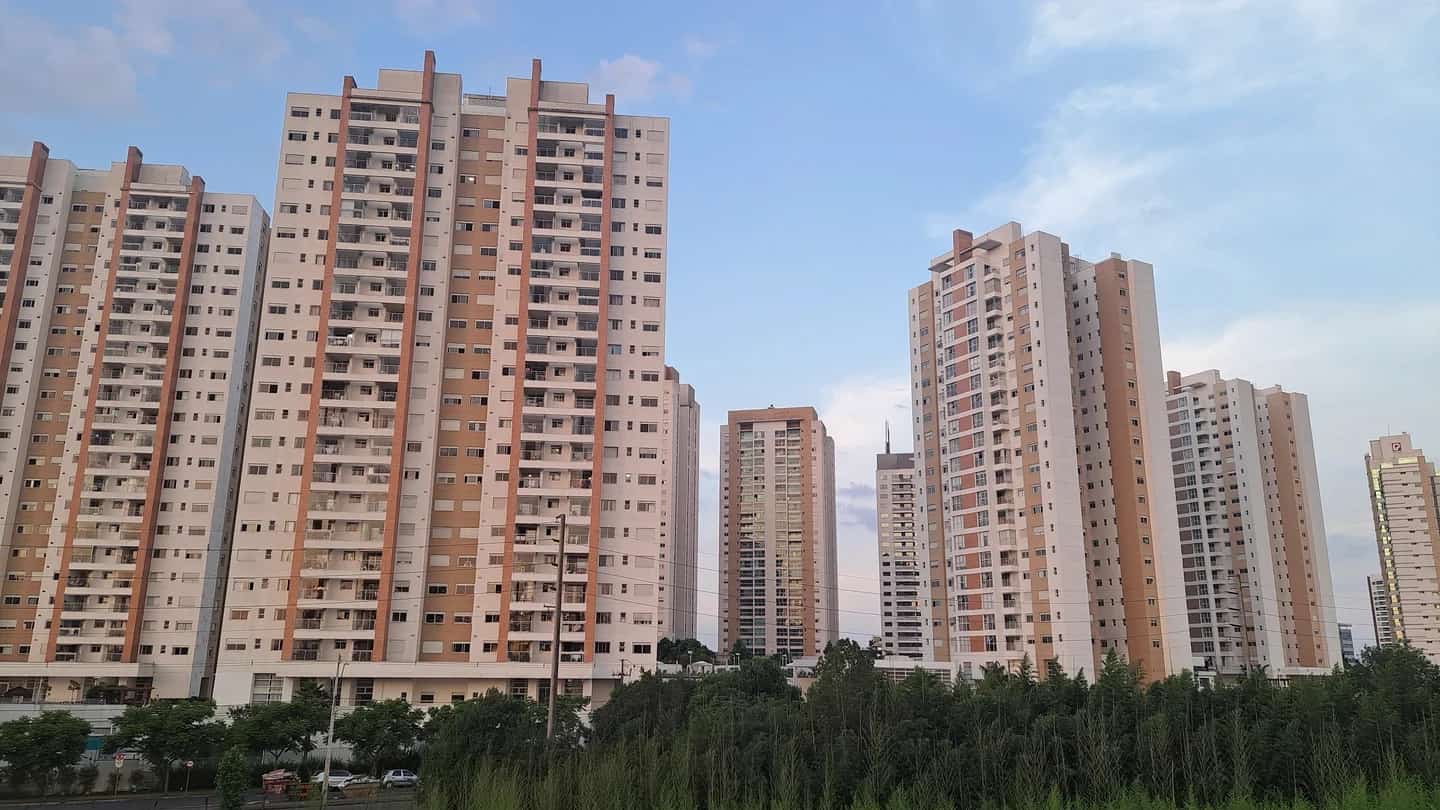 Conjunto de torres residenciais com árvores em primeiro plano, representando o mercado imobiliário brasileiro