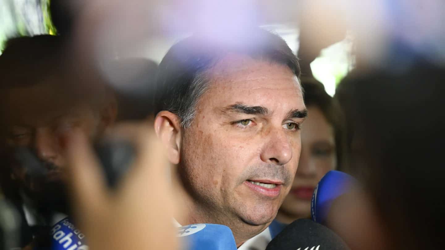 Flávio Bolsonaro cercado por microfones em entrevista coletiva