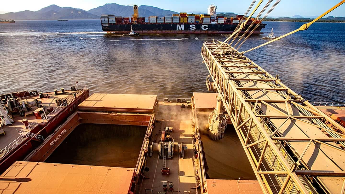 Terminal portuário com navios e guindastes usados na exportação de commodities