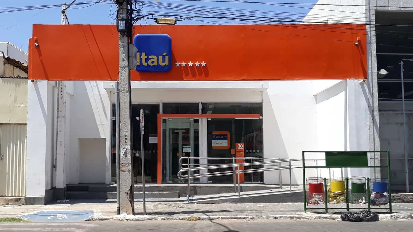 Agencia do Itau Unibanco em esquina de rua movimentada, com o logotipo da marca na fachada